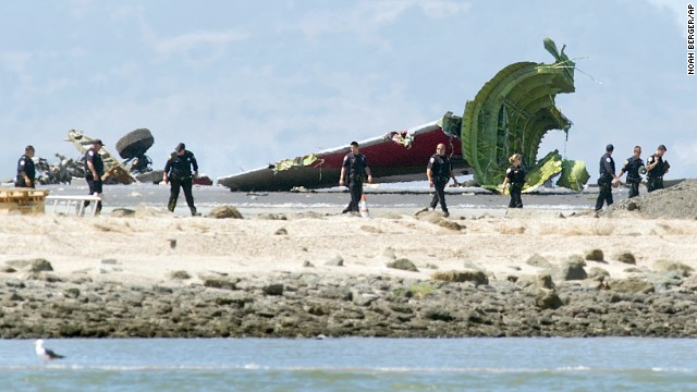 Investigators pass the detached tail and landing gear of Asiana Airlines Flight 214 on July 6.