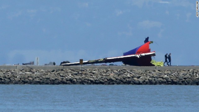 People walk past the wreckage of the plane's tail on July 6.