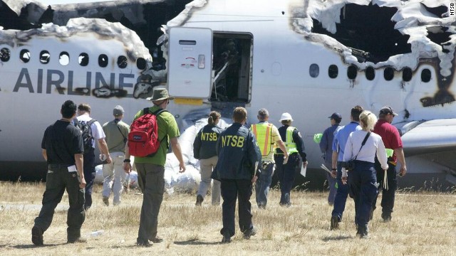 Investigators approach the crash in a handout photo released on July 7.