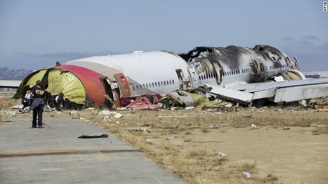 An investigator stands near the tail of the plane in a handout released on July 7. The NTSB has ruled out weather as a problem and said that conditions were right for a "visual landing."