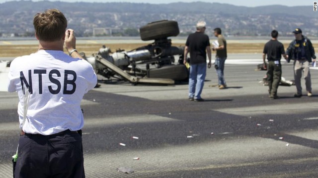 An investigator photographs part of the landing gear at the crash site in a handout released on July 7. The NTSB's preliminary assessment of the plane's cockpit and flight data recorders shows the flight was coming in too slow and too low. 