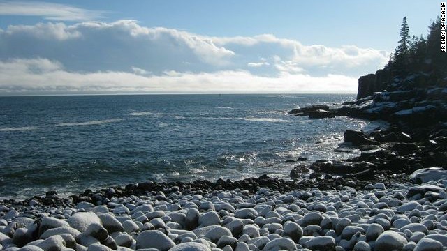 Otter Cliffs, noted for world-class rock climbing, overlooks a beach covered in cobblestones.