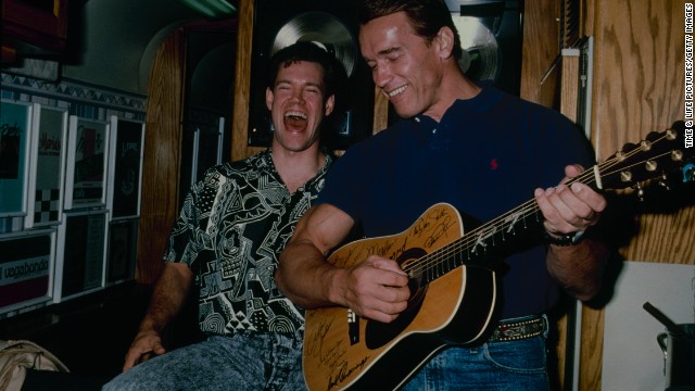 Travis laughs with Arnold Schwarzenegger in 1990.