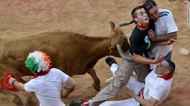 People are pushed by a bull in the bull ring in Pamplona on July 14.