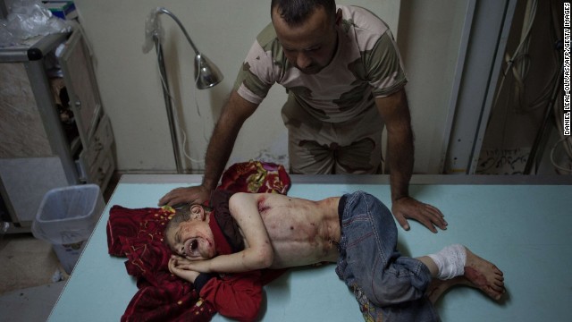 A Free Syrian Army fighter stands over a boy who was injured during shelling in Al-Bara on Monday, July 8. 