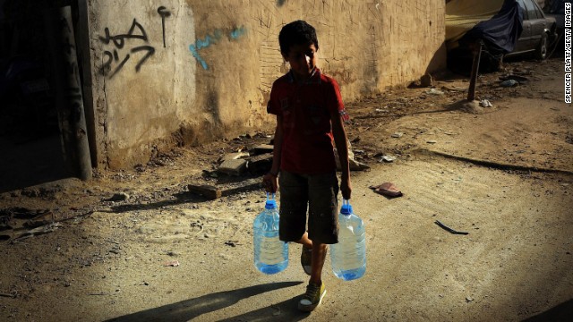 A boy walks with jugs of water on June 27 in a neighborhood in Beirut, Lebanon, with a high concentration of Syrian refugees. Since January, the number of Syrian refugees in Lebanon has more than tripled. 