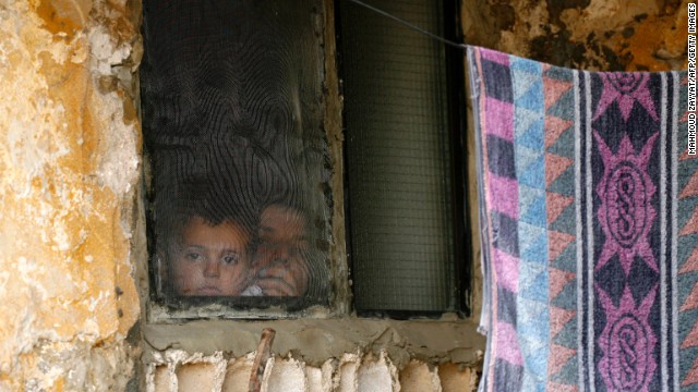 A Syrian woman and child look out of a refugee camp window on June 20 in Alman, Lebanon, after fleeing their hometown in Idlib province, Syria. 