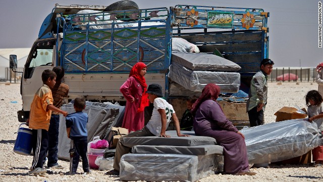 Syrian refugees stand with their belongings on June 20, World Refugee Day, at Zaatari refugee camp in Jordan.