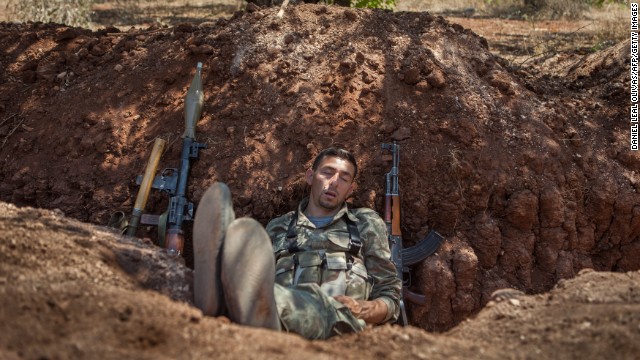 A rebel fighter naps in a trench about 300 feet from the Syrian government forces' positions along the highway connecting Idlib with Latakia on Monday, July 15.