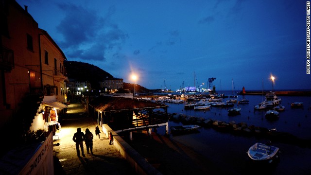 A couple walks along the port of Giglio at night on January 12, 2013.