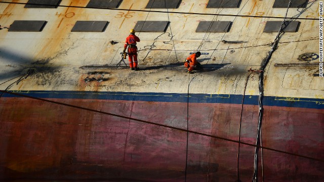 Workers stand on the edge of the ship on January 8, 2013.