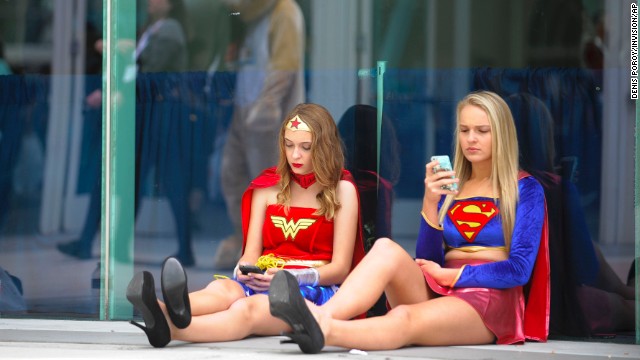 Joy Donaldson, left, dressed as Wonder Woman, and Everleigh Reed as Supergirl, take a break outside of the convention on July 20.