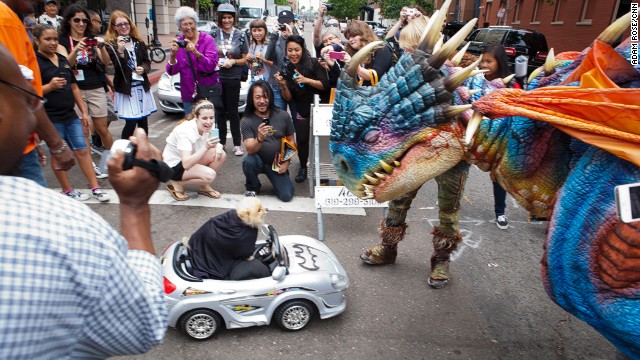 People gather around a dog dressed as Batman as it encounters a large, colorful creature on July 20.