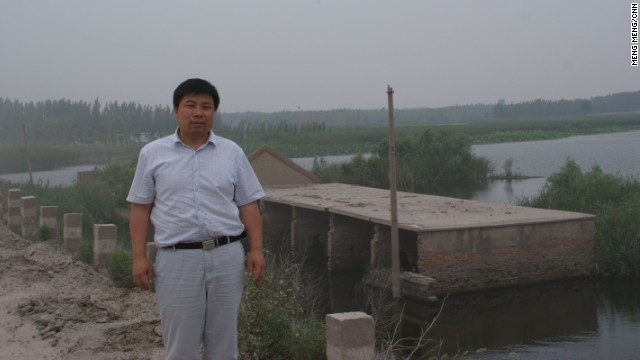 Xiao Guoqiang, a 50-year-old farmer stands before his sunken village in Jining, Shandong Province on June 26, 2013. Underground mining in this region is devouring 20 million square meters of land a year.