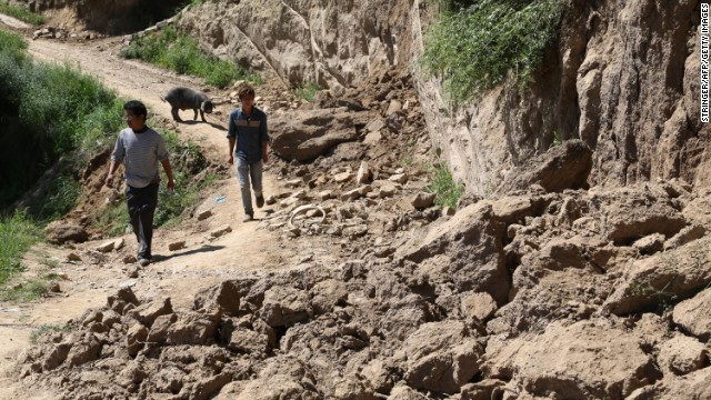 Two men make their way along a damaged road in Hetuo township in Dingxi on July 22. The original quake and powerful aftershocks caused roofs to collapse, cut telecommunications lines and damaged a major highway linking Gansu Province's capital of Lanzhou to the south, reports say.