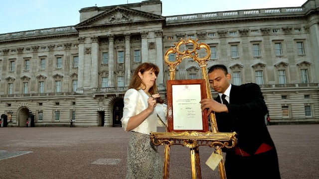 The queen's press secretary, Ailsa Anderson, left, and Badar Azim, a palace footman, place the official birth announcement on a golden easel in front of Buckingham Palace on July 22.
