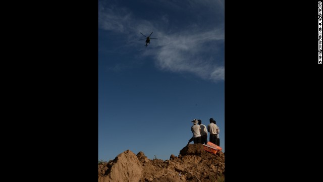 A helicopter airdrops relief supplies above Yongguang on July 22 as villagers wait on the ground.