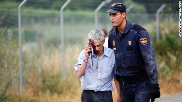 An injured passenger is helped from the scene by a police officer.