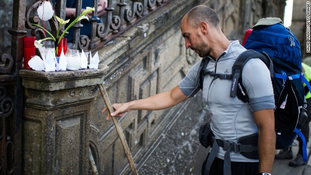 A man leaves his cane next to candles in memory of the train crash victims, on Friday, July 26, in Santiago de Compostela, Spain. A spokeswoman for the Galician regional government told CNN that at least 78 people were confirmed dead but that the number could rise to 80.