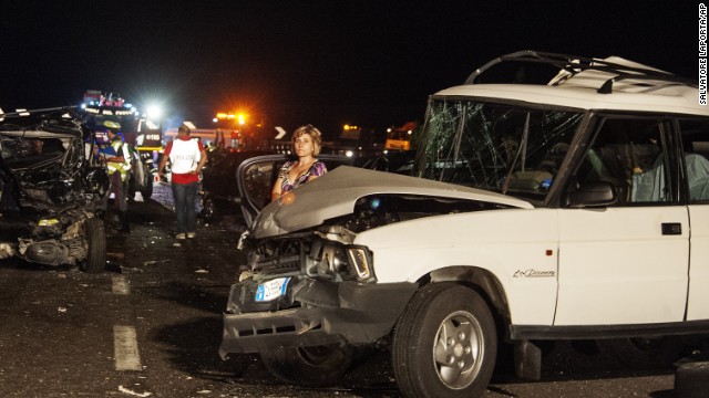 Damaged cars and debris litter the scene of the accident. 