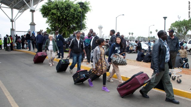 Travelers walk to be taken to hotels after the airport initially was closed August 7 following the fire. <!-- -->
</br>