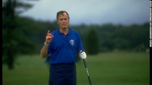 President George H. W. Bush pauses to speak to media while playing golf in Kennebunkport, Maine, in August 1990. 