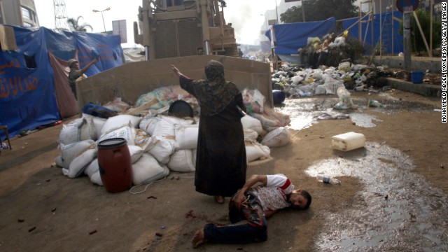 A woman tries to stop a military bulldozer from hurting a wounded youth during clashes on August 14, 2013, in eastern Cairo.