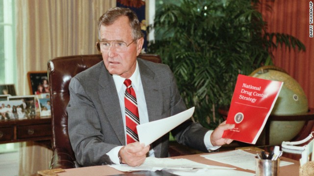 President George H. Bush holds up a copy of the National Drug Control Strategy during a meeting in the Oval Office on September 5, 1989. In a televised address to the nation, Bush asked Americans to join the war on drugs.