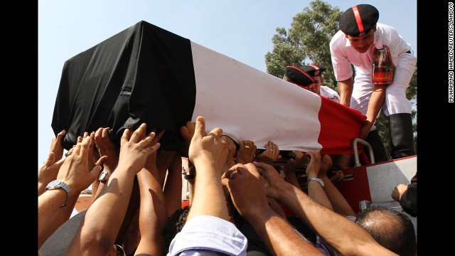 People reach for a coffin on Thursday, August 15, during a funeral for police officers killed during a crackdown at two protest camps in support of Morsy. 