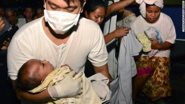 A medic carries 3-month-old Trisia Mae Kumaro as her mother steps out of an ambulance at the hospital on August 17. 
