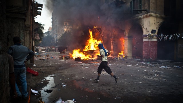 A supporter of the Muslim Brotherhood runs past a burning vehicle near Cairo's Ramses Square during clashes with security officers on August 16. 