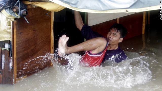 A man falls as he tries to fix the roof of his flooded home in Binakayan, Philippines, on August 19.