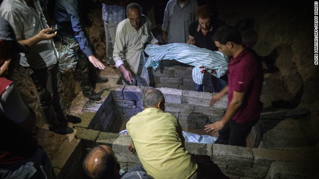 Men bury the bodies of six members of the same family killed in a bombing in Raqqa on Saturday, August 10.