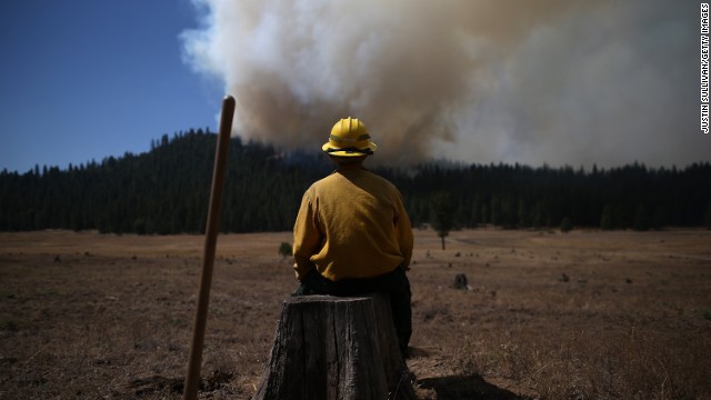 U.S. Fish and Wildlife Service firefighter Corey Adams sits on a tree stump as he monitors the Rim Fire near Groveland on August 25.