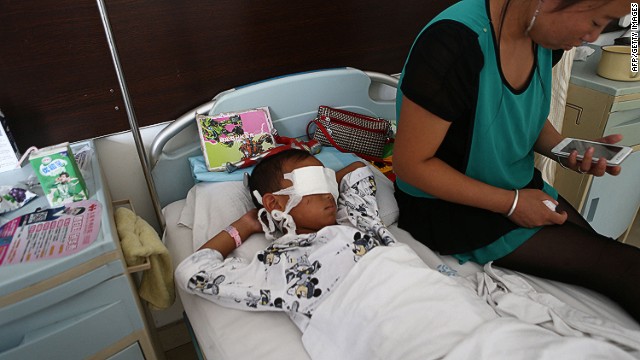 A boy lies with his eyes bandaged as his mother sits next to him at a hospital in Taiyuan, Shanxi province, China. 