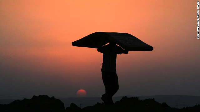 A Syrian-Kurdish man carries a mattress at sunset at the Quru Gusik refugee camp, east of Arbil, the capital of the autonomous Kurdish region of northern Iraq, on Tuesday, August 27. More than 50,000 Syrian refugees have crossed into Iraq's Kurdish region in less than two weeks as authorities rush to house them in more permanent camps.