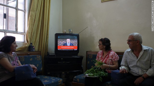 Syrians listen to a televised speech by al-Assad in Damascus on June 3, 2012. Al-Assad said that his government faces a foreign plot to destroy Syria and blamed "monsters" for the Houla massacre in a rare televised speech delivered in parliament. 