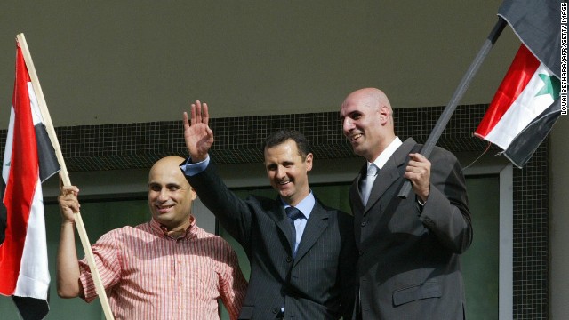 Two unidentified supporters of al-Assad join him on the balcony as he celebrates the referendum results in Damascus on May 29, 2007. Al-Assad won a second seven-year mandate after netting 97% of the vote in a referendum boycotted by the opposition.