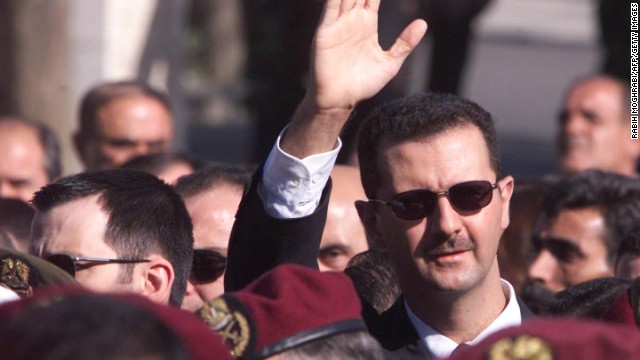 Al-Assad waves to supporters as he marches behind the coffin during his father's funeral in Damascus on June 13, 2000.