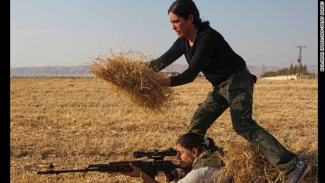 A Syrian Kurd uses hay to hide another woman in a training session organized by the Kurdish Women's Defense Units on Wednesday, August 28, in a northern Syrian border village. They're preparing if the area comes under attack. 