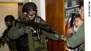 Elian Gonzalez, then 6, cowers in the arms of Donato Dalrymple on April 22, 2000, as federal officers charge in to take custody of the boy. 