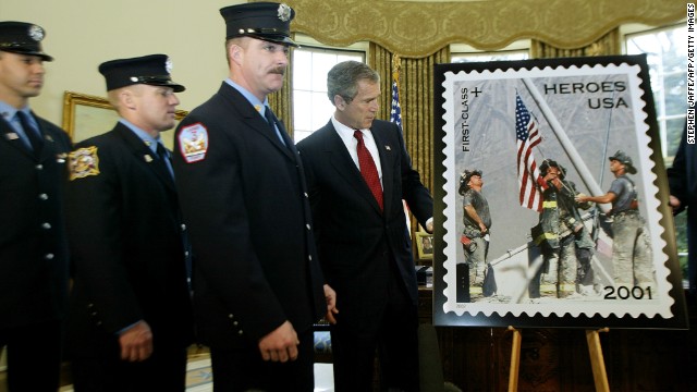 President George W. Bush unveils a "Heroes of 2001" stamp issued by the Postal Service on March 11, 2002, to raise funds to assist the families of emergency relief workers killed or permanently disabled as a result of the World Trade Center attacks. He is joined at the White House by the firefighters who are featured in the image, from left, Eisengrein, Johnson and McWilliams. 