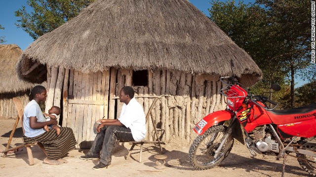 Palikobila Mwembe, an environmental health technician in the Binga district of Zimbabwe who takes part in the Riders for Health program, talks with a mother about her baby.