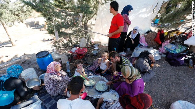 Syrian refugees who failed to find shelters in a refugee camp eat and rest by the side of a road a few meters away from the Turkish-Syrian border on Thursday, September 5. 