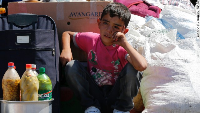 A Syrian boy sits beside his family's belongings on Friday, September 6, as they wait for a vehicle to pick them up after entering Turkey from the Turkish border gate of Cilvegozu.