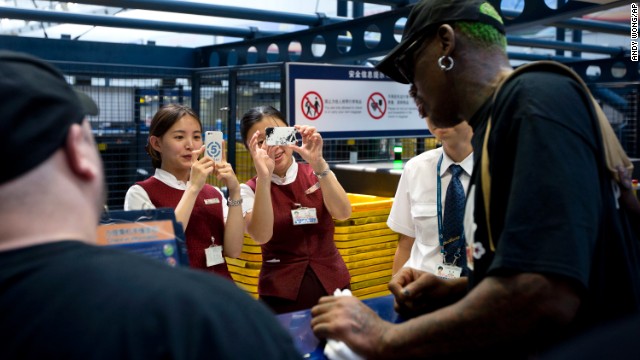 Airport staff take pictures of the former NBA star at a check-in counter at China's Beijing Capital International Airport on September 3 while he was heading to North Korea. 