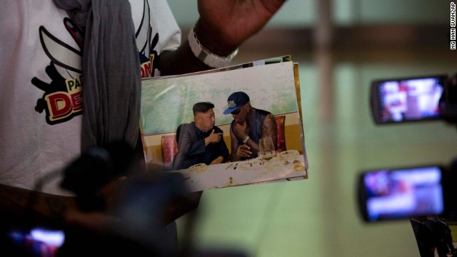 Rodman shows a photo of himself with North Korean leader Kim Jong Un as he arrives at the Beijing airport on September 7. At a news conference Monday, September 9, he called Kim a "very good guy."