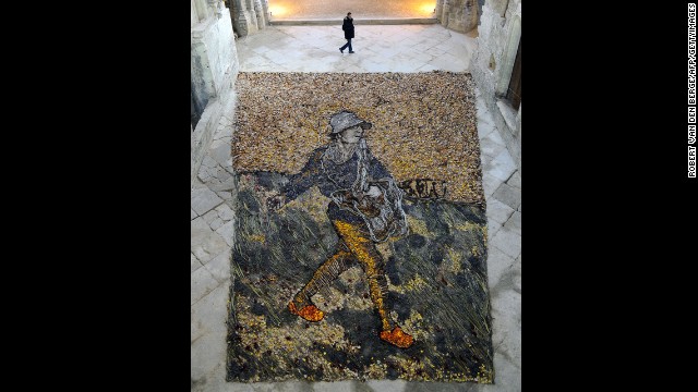 A man walks past a recreation of van Gogh's "The Sower" made by Brazilian artist Vik Muniz with branches, leaves and dried flowers.