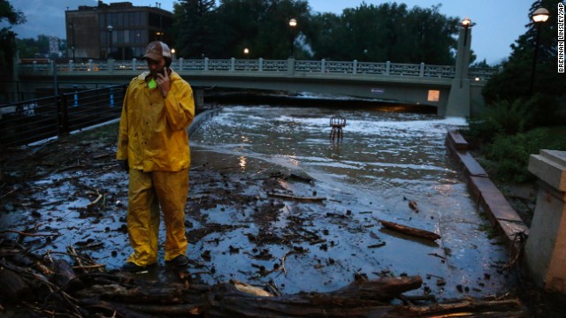 A city worker talks on his phone while surveying high water levels from Boulder Creek after flash flooding in downtown Boulder, Colorado, on September 12.