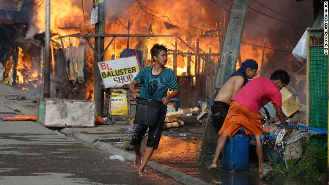Residents try to put out fire that gutted several homes while government troopers continue their assault at Muslim rebels on September 12 in Zamboanga City.